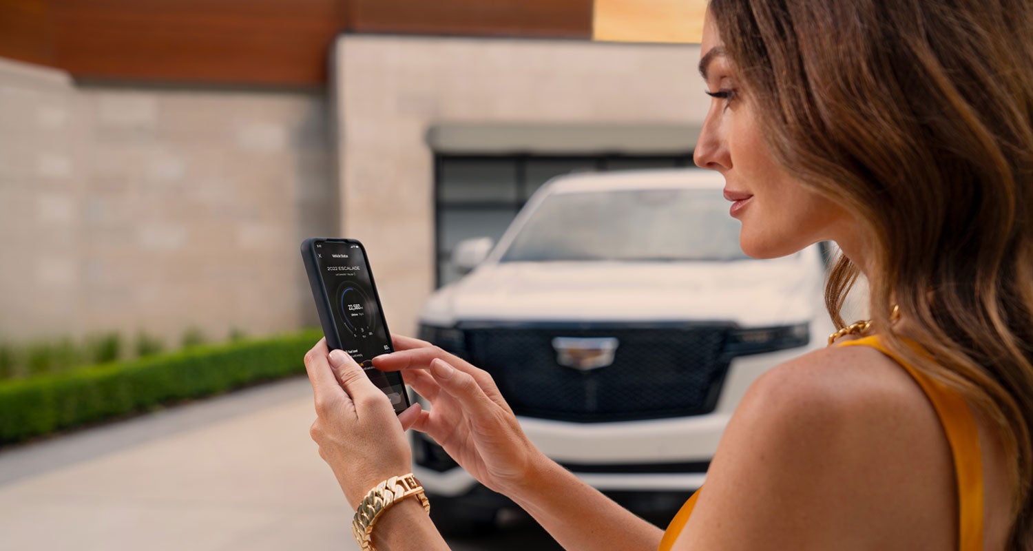 lady checking her mobile with a Cadillac vehicle background | Garlyn Shelton Cadillac in Temple TX